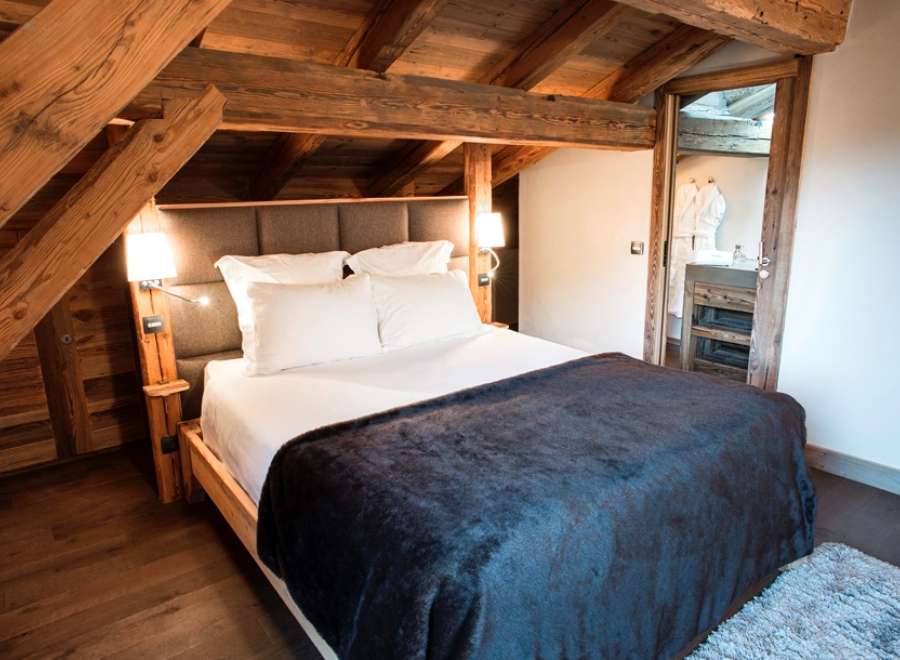 Cozy up in this rustic-chic bedroom featuring exposed wooden beams and a plush throw blanket.