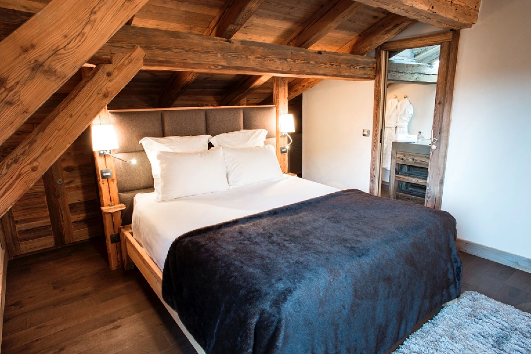 Cozy up in this rustic-chic bedroom featuring exposed wooden beams and a plush throw blanket.