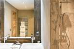 Luxurious bathroom with double sinks, wooden vanity, and a walk-in shower.