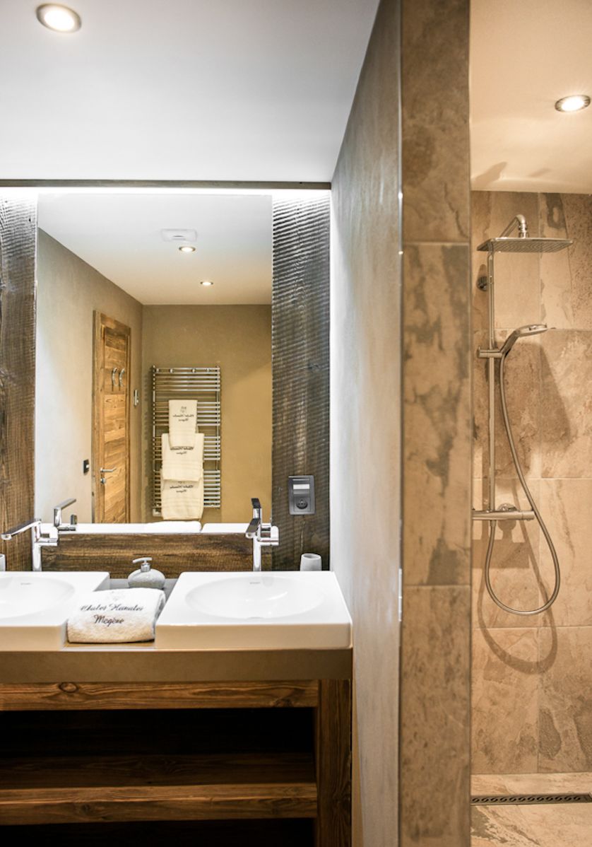 Luxurious bathroom with double sinks, wooden vanity, and a walk-in shower.