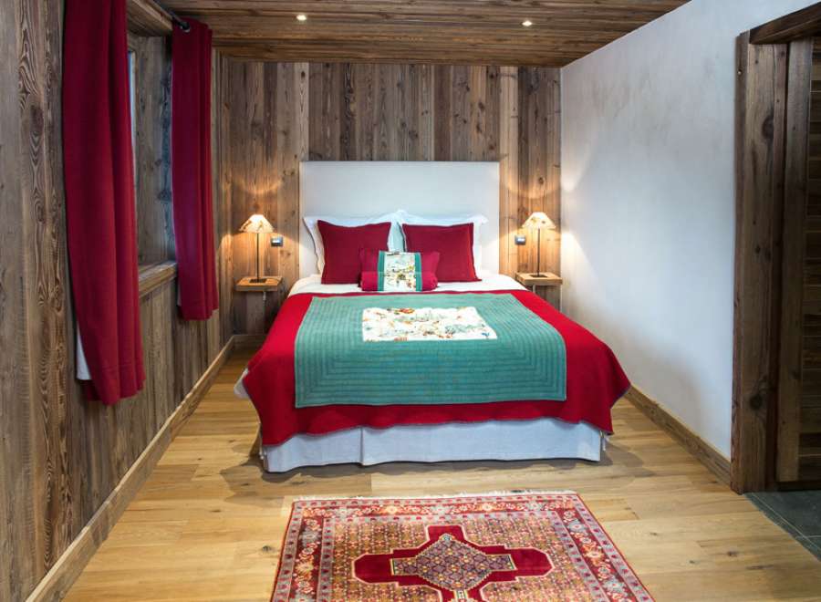 Cozy chalet bedroom with rustic wood walls and red accents.