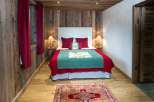 Cozy chalet bedroom with rustic wood walls and red accents.