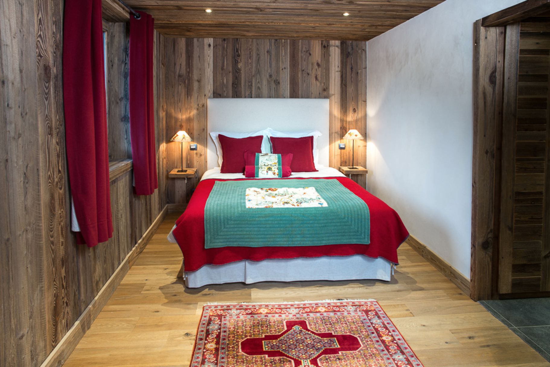 Cozy chalet bedroom with rustic wood walls and red accents.