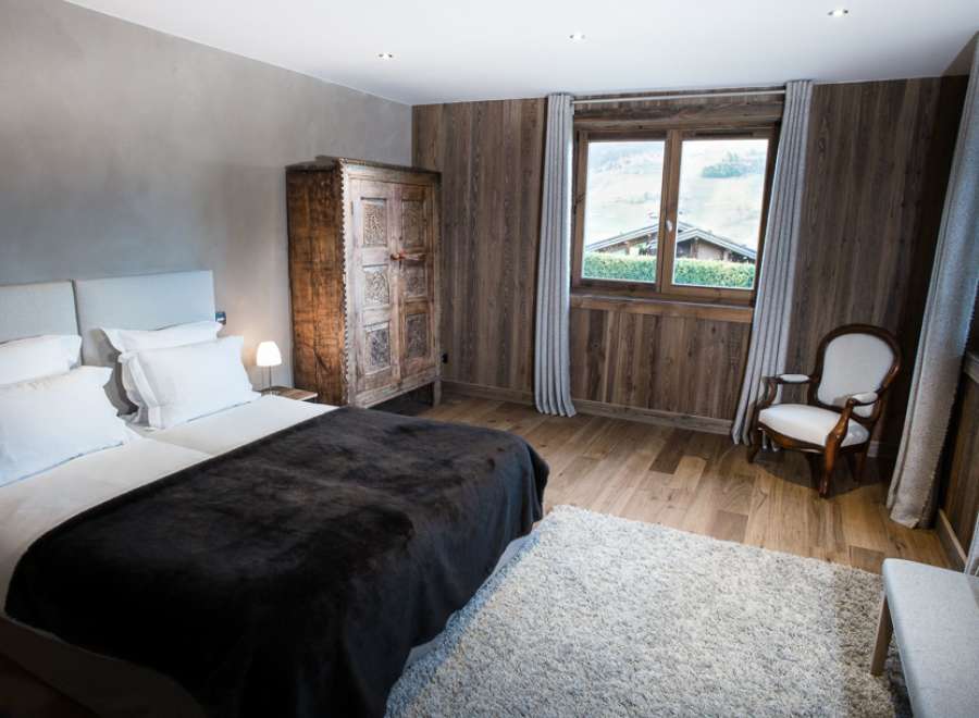 Cozy bedroom with wooden walls and a large window offering scenic views.