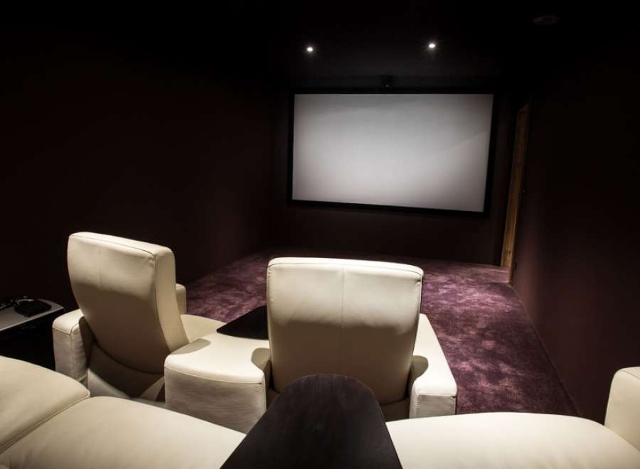 Luxurious home theater with plush, off-white leather seating and a large projection screen.