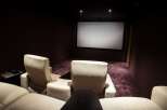 Luxurious home theater with plush, off-white leather seating and a large projection screen.