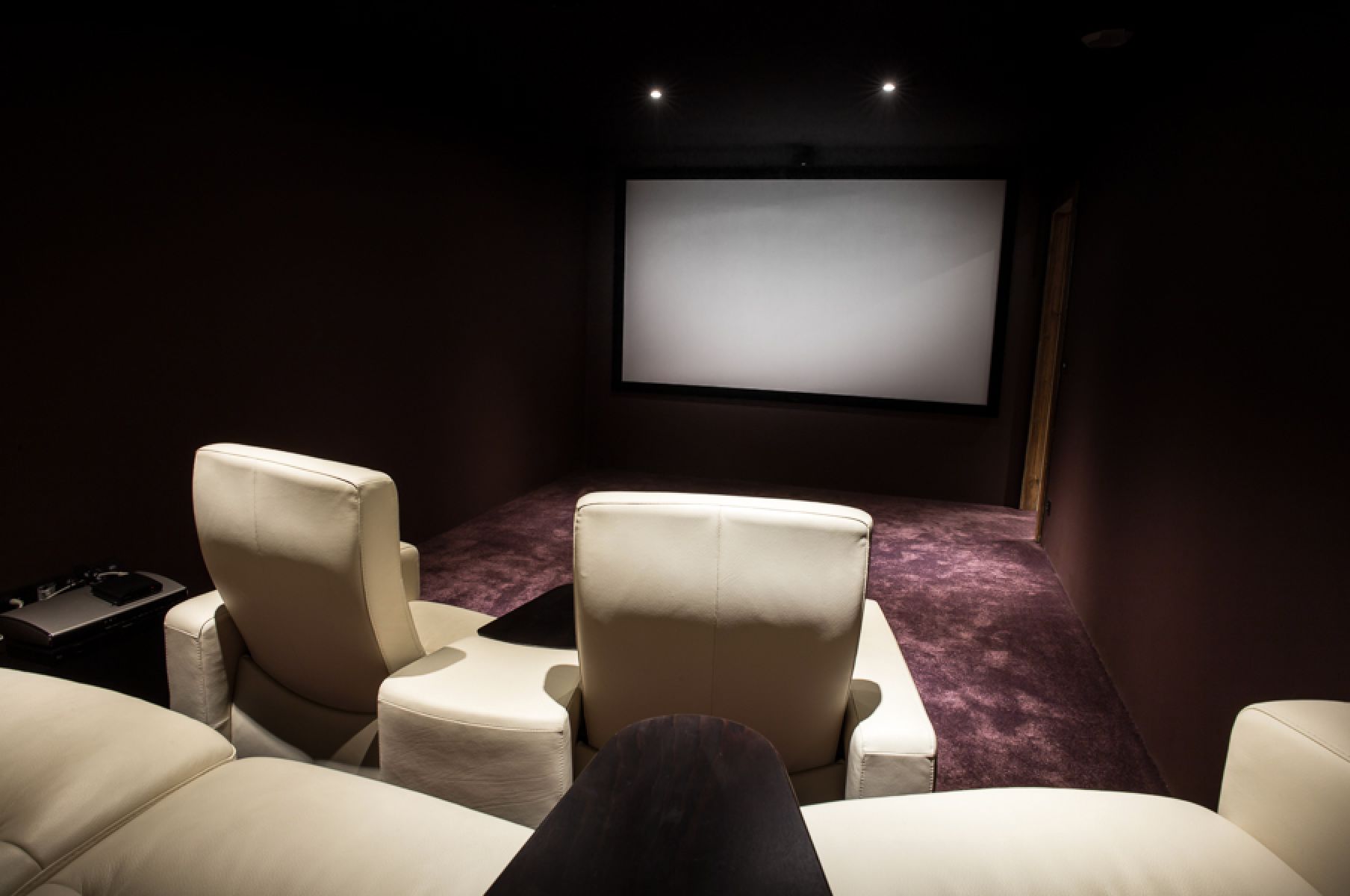 Luxurious home theater with plush, off-white leather seating and a large projection screen.