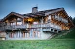 Luxury chalet with stunning mountain views, featuring spacious balconies and large windows.
