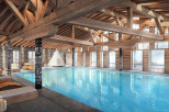 Indulge in luxury at this stunning chalet featuring a spacious indoor pool, surrounded by wooden beams and large windows offering breathtaking views.