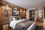 This stunning hotel room boasts a cozy, rustic-chic design with exposed wood walls and a plush bed.
