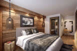 This stunning hotel room boasts a cozy, rustic-chic design with exposed wood walls and a plush bed.