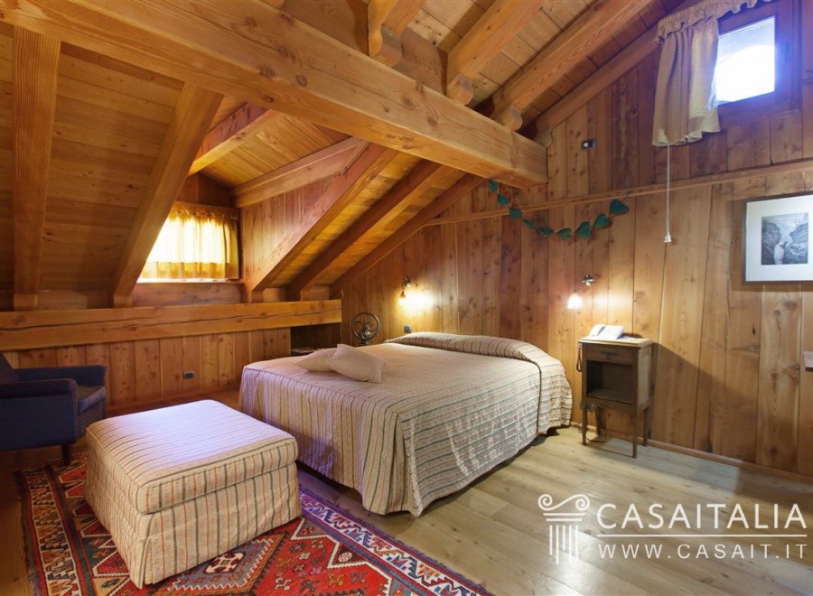 Cozy wooden bedroom with a double bed, ottoman, and armchair.