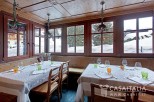 This charming restaurant boasts a rustic-chic ambiance with wooden paneling and large windows offering stunning snowy mountain views.