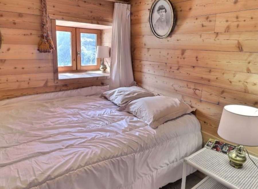 Cozy bedroom with wooden walls and a comfortable bed.