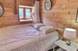Cozy bedroom with wooden walls and a comfortable bed.