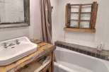 Rustic bathroom with vintage sink and wooden vanity.