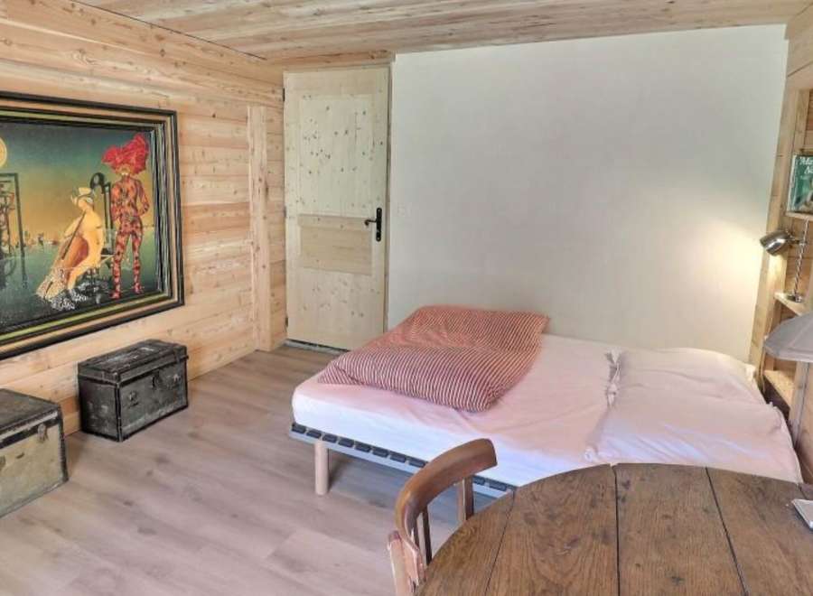 Cozy chalet bedroom with unique artwork, wooden walls, and comfortable bed.
