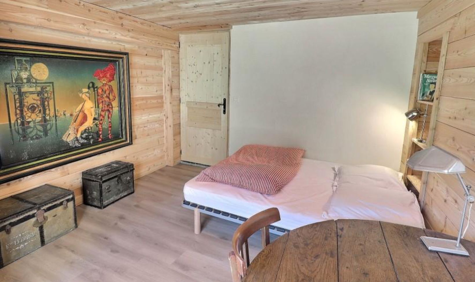 Cozy chalet bedroom with unique artwork, wooden walls, and comfortable bed.