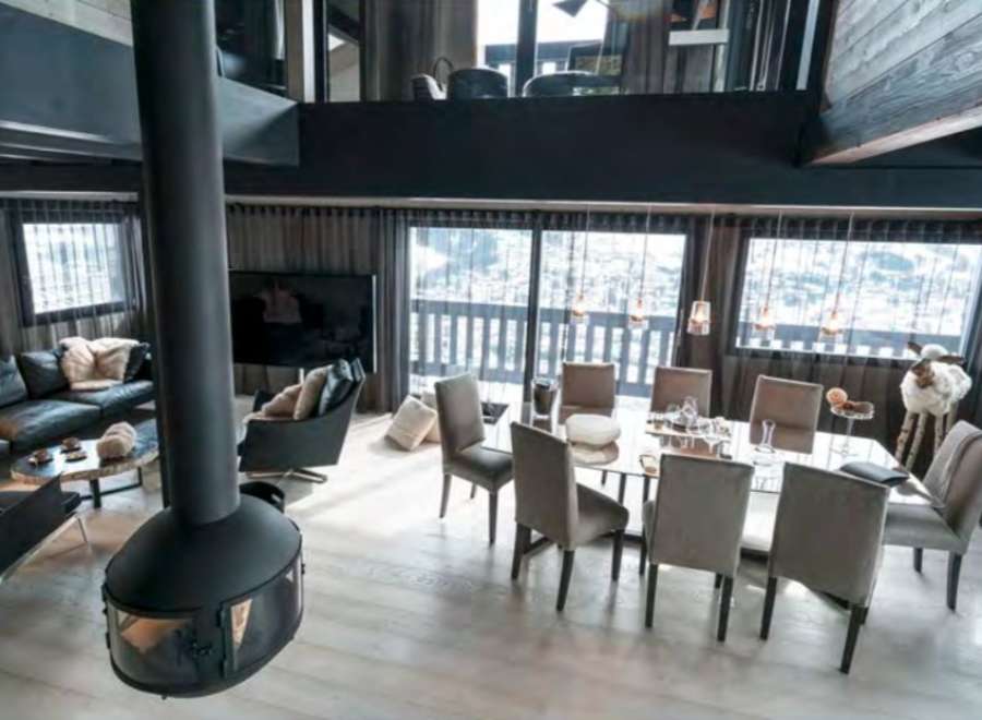 This stunning chalet boasts a spacious open-plan living area with floor-to-ceiling windows offering breathtaking mountain views.