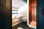 Luxury bathroom with copper mosaic tile shower, built-in shelving, and a modern toilet.