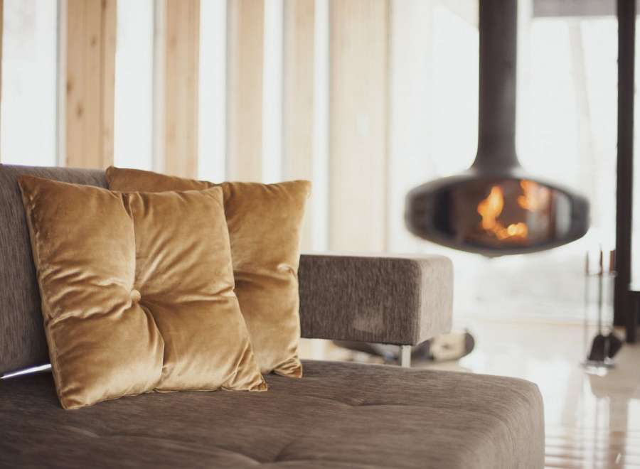 Cozy up by the fireplace in this stunning living room, featuring plush velvet cushions and a modern design.