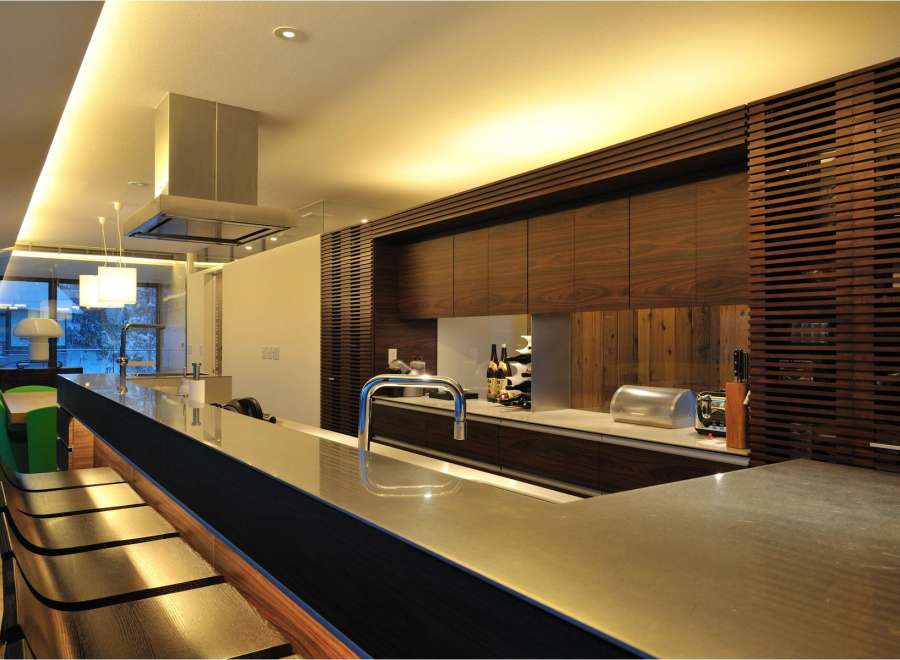 This stunning kitchen boasts a sleek, modern design with a long island featuring a metallic countertop and built-in seating.