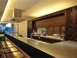 This stunning kitchen boasts a sleek, modern design with a long island featuring a metallic countertop and built-in seating.