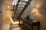 Modern hallway with sleek glass and metal staircase, illuminated by warm lighting.