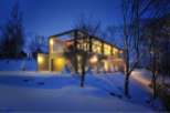 Stunning modern home nestled in a snowy landscape, featuring a sleek design with expansive windows and a spacious garage.