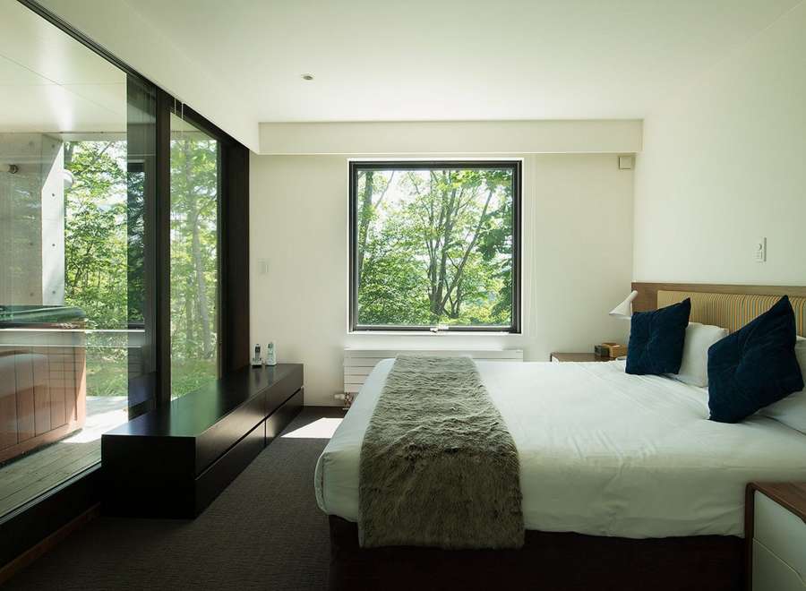 Wake up to stunning views of lush greenery from this luxurious bedroom.