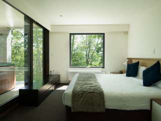 Wake up to stunning views of lush greenery from this luxurious bedroom.