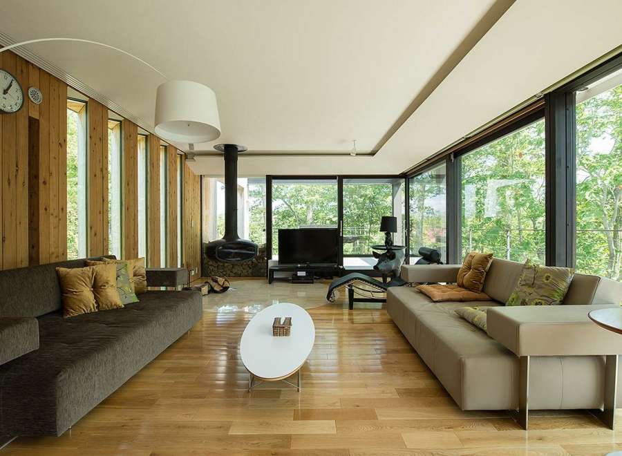 Stunning modern living room with floor-to-ceiling windows showcasing lush greenery.
