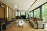 Stunning modern living room with floor-to-ceiling windows showcasing lush greenery.