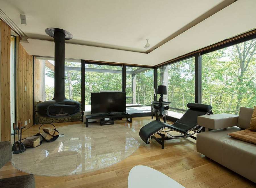 Stunning modern living room with floor-to-ceiling windows showcasing breathtaking forest views.