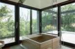 Luxurious bathroom with a wooden bathtub and floor-to-ceiling windows offering breathtaking views of nature.