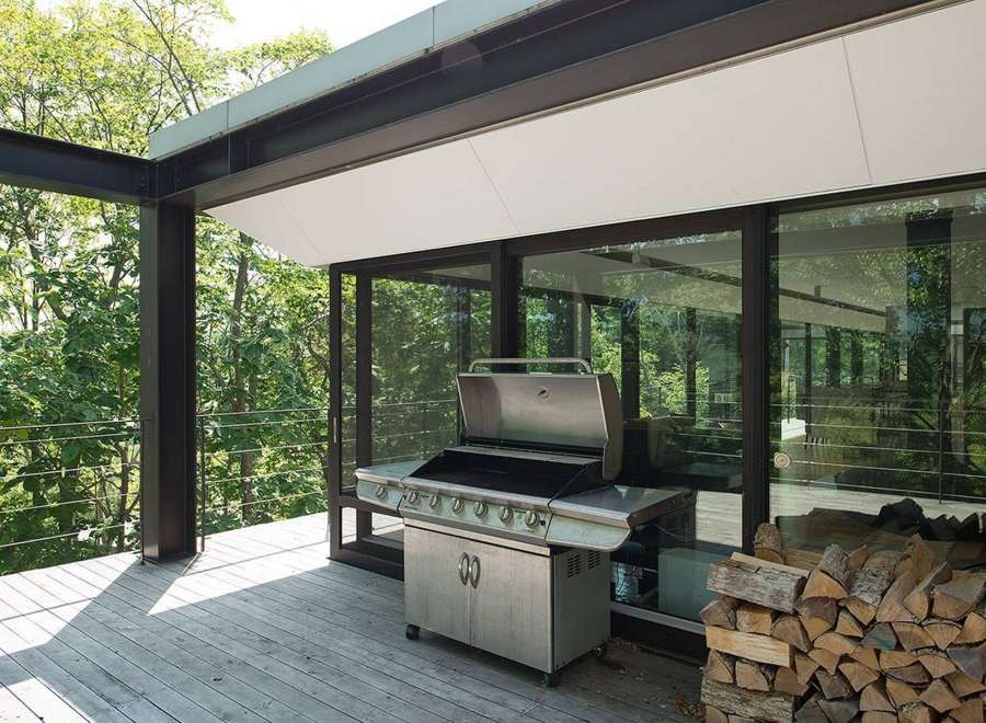Modern outdoor kitchen with stainless steel grill and woodpile, perfect for summer barbecues.