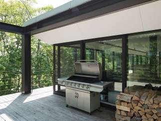 Modern outdoor kitchen with stainless steel grill and woodpile, perfect for summer barbecues.
