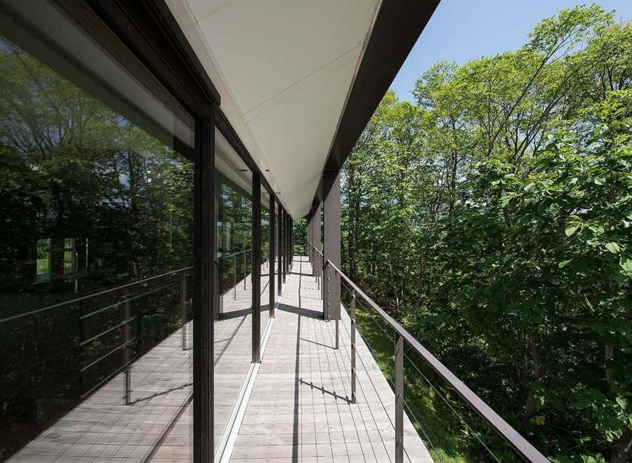 This stunning property boasts a modern design with expansive windows offering breathtaking views of the lush forest.