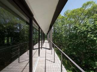 This stunning property boasts a modern design with expansive windows offering breathtaking views of the lush forest.