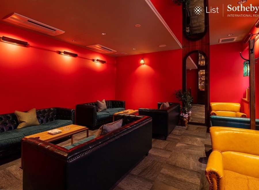 Luxurious red-walled lounge with plush leather sofas and armchairs, perfect for relaxing and socializing.