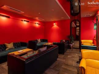 Luxurious red-walled lounge with plush leather sofas and armchairs, perfect for relaxing and socializing.