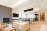 Modern living space with open-plan kitchen and dining area, featuring a sleek fireplace and large windows.