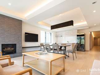Modern living space with open-plan kitchen and dining area, featuring a sleek fireplace and large windows.