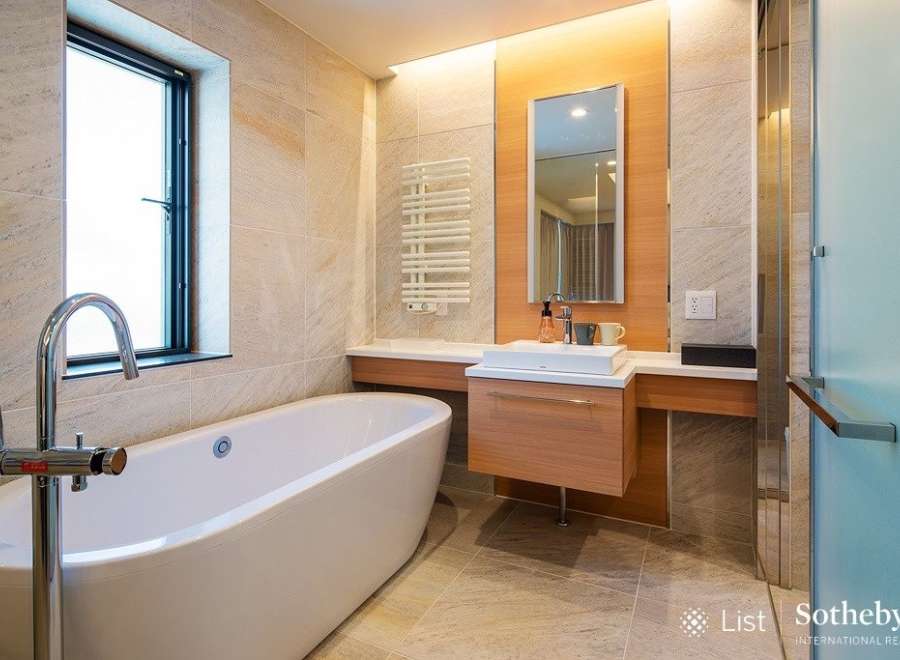 Luxurious bathroom boasts a freestanding bathtub, modern vanity with sleek cabinetry, and a frameless glass shower enclosure.
