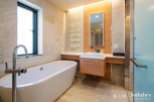 Luxurious bathroom boasts a freestanding bathtub, modern vanity with sleek cabinetry, and a frameless glass shower enclosure.