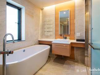 Luxurious bathroom boasts a freestanding bathtub, modern vanity with sleek cabinetry, and a frameless glass shower enclosure.