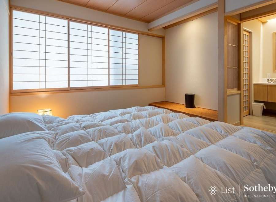 Experience serene living in this exquisitely designed bedroom, featuring a plush, white comforter and traditional Japanese shoji screens that filter soft, natural light.