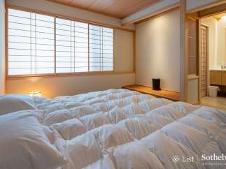 Experience serene living in this exquisitely designed bedroom, featuring a plush, white comforter and traditional Japanese shoji screens that filter soft, natural light.