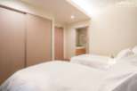 This luxurious bedroom features twin beds with crisp white linens, a built-in closet with sliding doors, and an ensuite bathroom with modern fixtures.