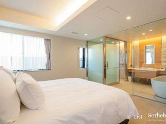 Luxurious bedroom with ensuite bathroom featuring a freestanding bathtub and glass enclosure.